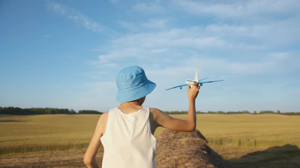 Funny Boy Runs Through the Haystacks and Playing with Airplane Near Wheat Field Boy Dreams of Being