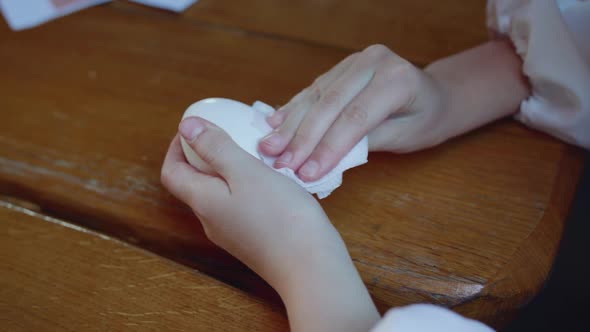 Young Girl's Hands Wipe Eggs for Painting at Wooden Table alt