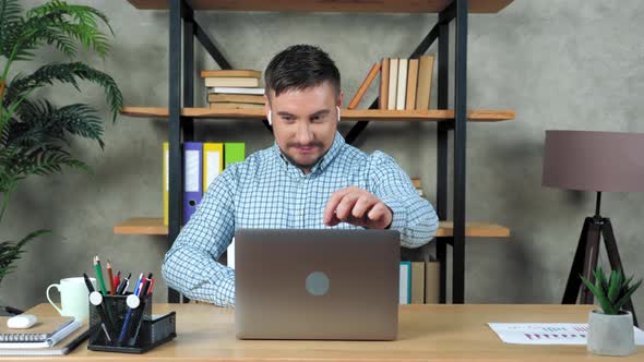 Smiling student man sitting on chair at desk in home open and start using laptop alt