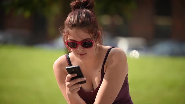 Young Woman In Park Sending SMS 1