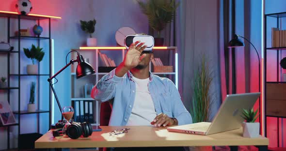 Guy Sitting at His Workplace in Home Office in the Evening and Working on Virtual Screen alt