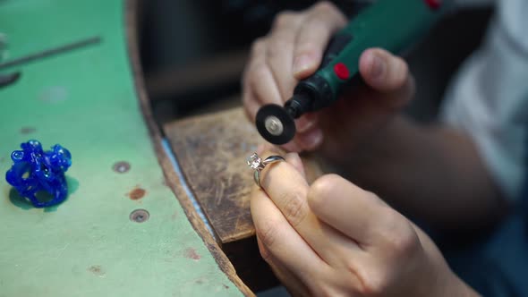 Closeup Female Hands Polishing Gemstone on Ring with Tool in Slow Motion alt