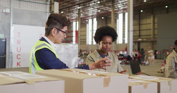 Diverse male and female workers with boxes talking in warehouse alt