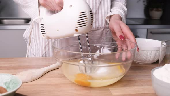 Beating Eggs And Mixing With Sugar Using Electric Mixer In A Glass Bowl. close up alt