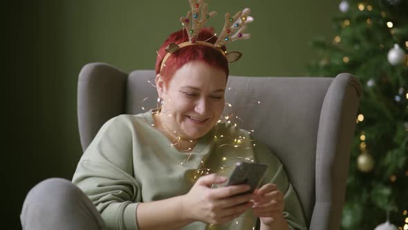 Woman Reads Writes Merry Christmas and Happy New Year Greetings on Smartphone
