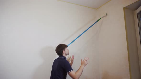 Adroit Caucasian Man Unusual Way Paints Wall with Roller That Rests on Forehead alt