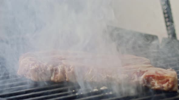 Slow motion of a large beef sirloin steak grilled on a charcoal grill