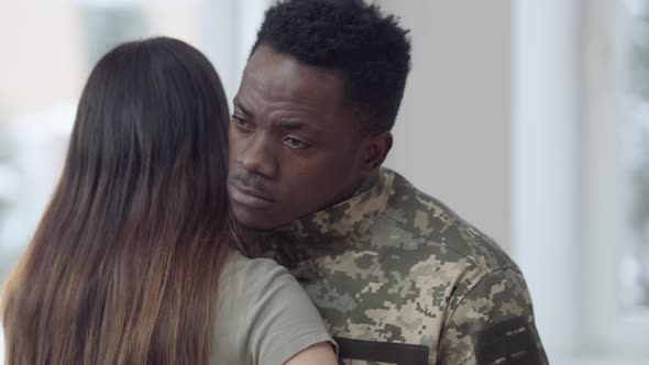 Portrait of Young Handsome African American Man in Army Uniform Hugging Caucasian Woman Looking Away alt