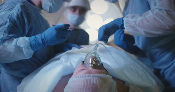 Surgical Team in Blue Suits Using Medical Instruments and Performing Surgical Operation alt