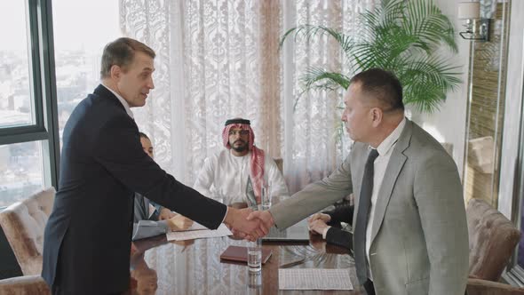 Middle-Aged Business Men Shaking Hands At Conference alt