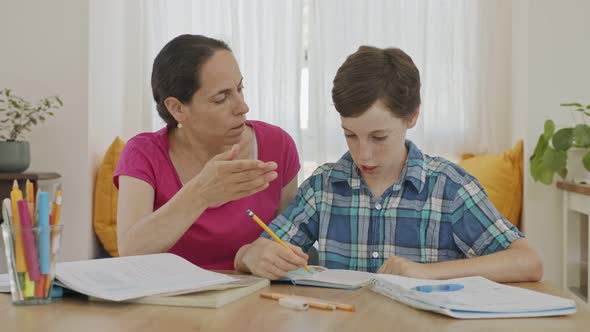 Mother helping her young son prepare homework during homeschooling alt