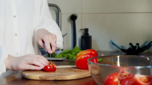 Woman Slicing Bell Pepper at Chopping Board on Kitchen Counter Indoors alt