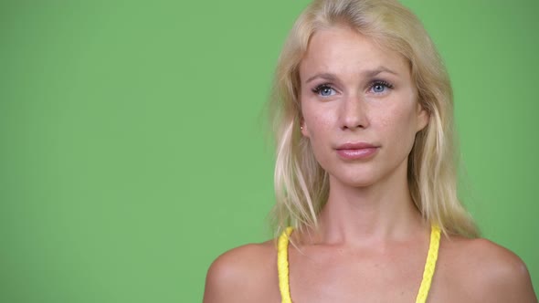 Young Beautiful Blonde Woman Thinking Against Green Background