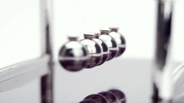 Slow motion shot of Newton's metal balls on white background. Close up.