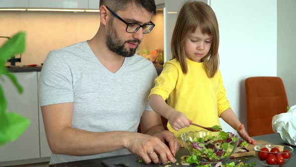 Father and Daughter Prepare Salad of Vegetables in Kitchen
