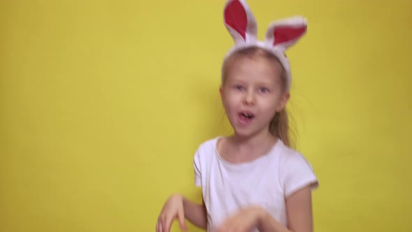 Cute Little Girl with Bunny Ears Looking at Camera and Jumping While Pretending To Be Rabbit During