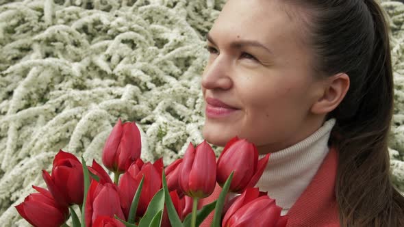 Portrait of a Happy Young Woman with a Bouquet of Red Tulips