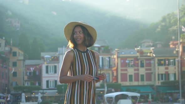 A woman walking wearing hat and backpack purse traveling, Portofino, Italy, luxury resort, Europe alt
