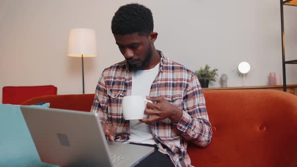 Young Man Using Laptop Computer Lying on Sofa at Home Working Online Shopping From Home Office alt