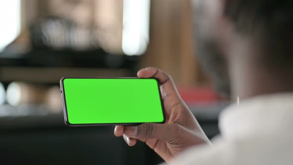 Rear View of African Man Using Smartphone with Chroma Key Screen  alt