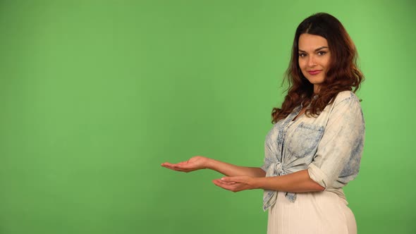 A Young Beautiful Caucasian Woman Presents Something to the Camera with a Smile  Green Screen