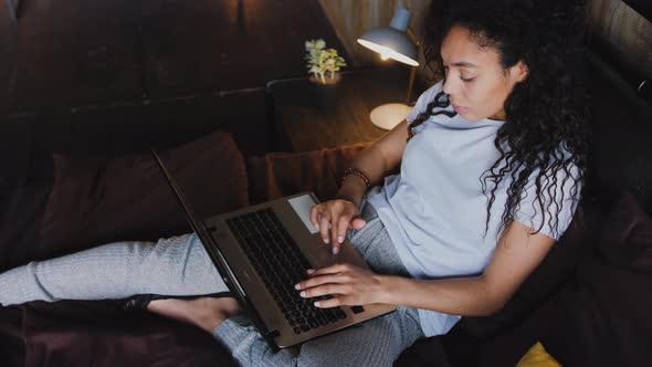 Young Attractive AfricanAmerican Woman Using Laptop Computer in the Bed Portrait High Angle View alt