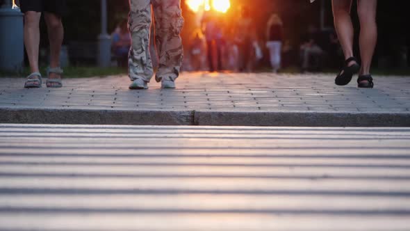 People Walk in the Evening City at Sunset, in the Frame You Can See the Man's Togas in Camouflage alt