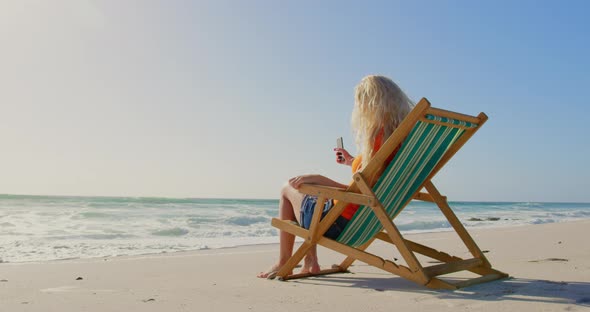 Woman relaxing on sun lounger at beach in the sunshine 4k