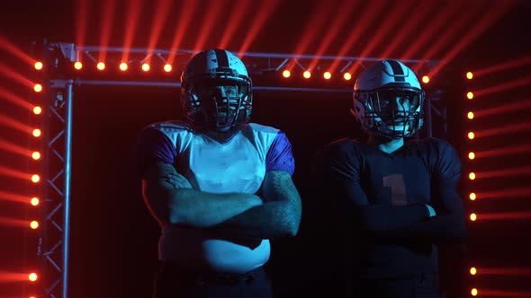 Two Confident Professional Quarterbacks Stand on the Field Against a Backdrop of Red Light and Smoke alt