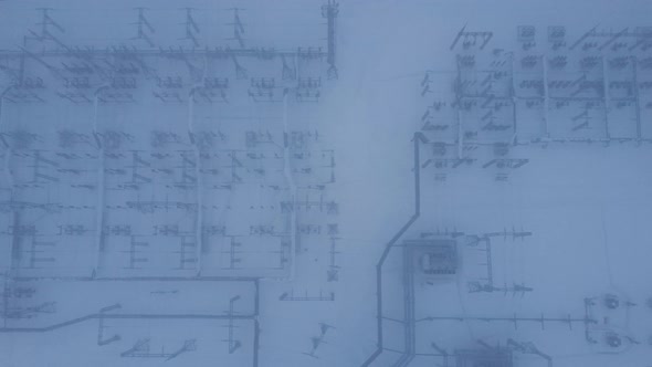 Aerial view of a high voltage electrical substation in cold snowy winter season. alt