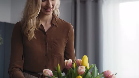 Caucasian woman putting fresh tulips into the vase. Shot with RED helium camera in 8K. alt