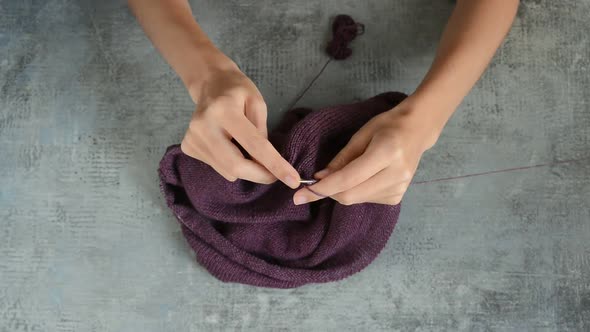 Young womans hands knitting with metal needles and dark red cotton thread