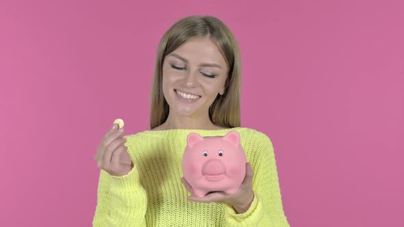 Ambitious Young Girl Inserting Coin in Piggy Bank, Pink Background alt