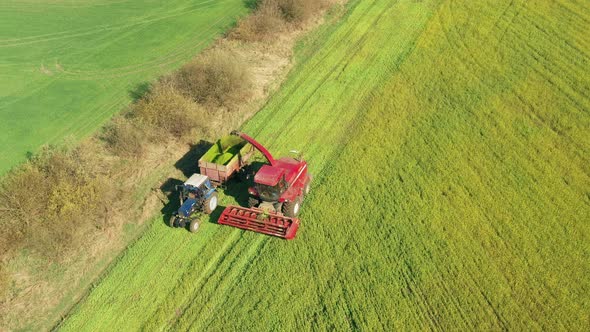 Aerial Elevated View Of Combine Harvester And Tractor Working Together In Field alt