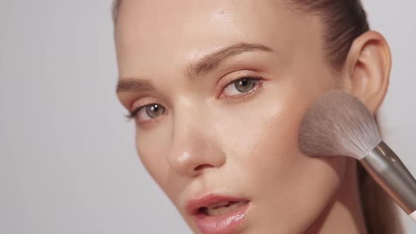 Nude Makeup Woman Applying Blush on Face Skin alt