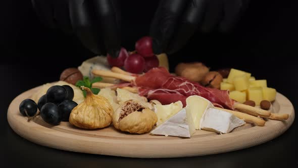 Preparation of cheese plate: parmesan, grapes, honey, nuts, grissini, jamon, prosciutto alt