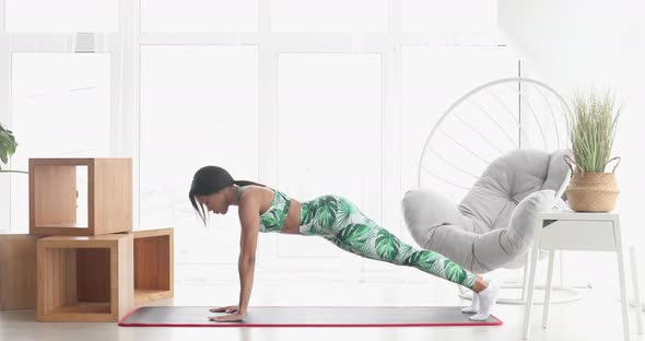 Concentrated slim black woman standing in plank position.