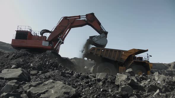 Excavator Lifts Bucket Filled with Coal and Pours It Into Mining Truck