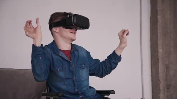 Adult Man in Wheelchair Using Virtual Reality Glasses and Sittin