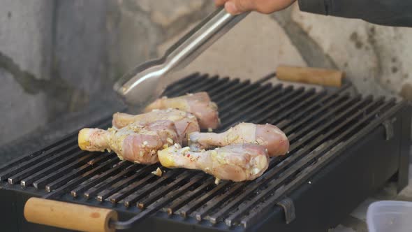 Man Puts Chicken Legs on the Grill
