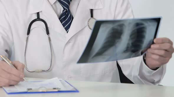 Pulmonology Doctor Looking at Lung Scan, Making Prescription for Sick Patient alt