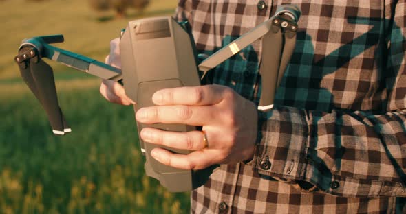 Close up shot of male person preparing drone for flight in nature during sunset. alt