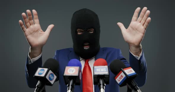 Criminal politician wearing a balaclava and talking to the media