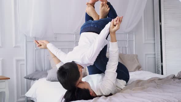 The Kid a Boy Plays with Her Mother at Home Laughs and Flies Like an Airplane in Her Mother's Arms alt