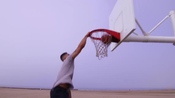 A man does a slam dunk while playing one-on-one basketball hoops on a beach court