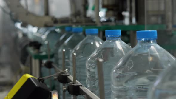Full five-liter bottles move along the conveyor. Drinking water production line alt