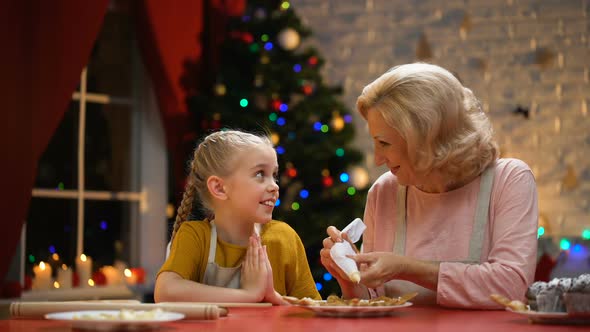 Cheerful Granny and Girl Decorating Cookies for Christmas Party, Happy Holidays alt