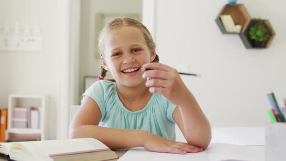Portrait of caucasian girl holding a pencil smiling looking at the camera at home alt
