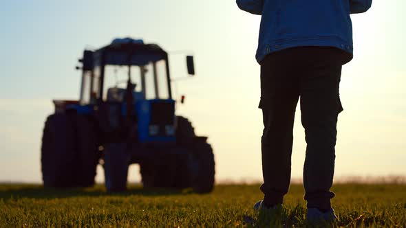 Silhouette Male Farmer Walking in a Green Field Against Sunset alt