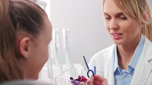 Teenage girl choosing the color of rubber bands for braces alt